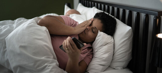 Frau liegt im Bett und kann nicht schlafen