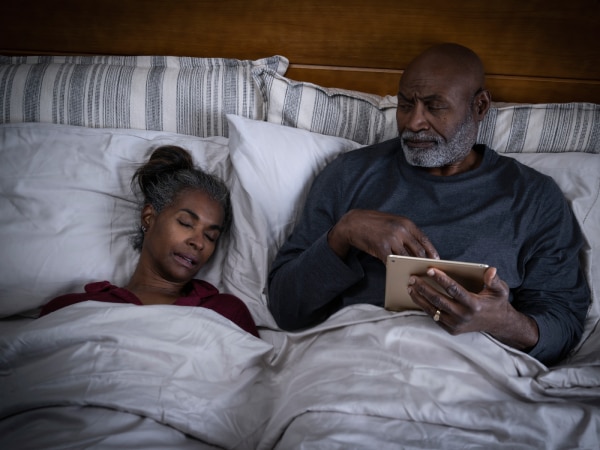  Une femme ronfle dans le lit tandis que l'homme semble agacé.